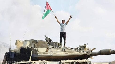 Un hombre con una bandera palestina sobre un tanque de las FDI.