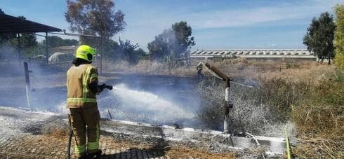 Un bombero apaga el fuego causado por un cohete lanzado desde Gaza en una granja lechera en Kfar Ahim. (Dror) Un bombero apaga el fuego causado por un cohete lanzado desde Gaza en una granja lechera en Kfar Ahim.