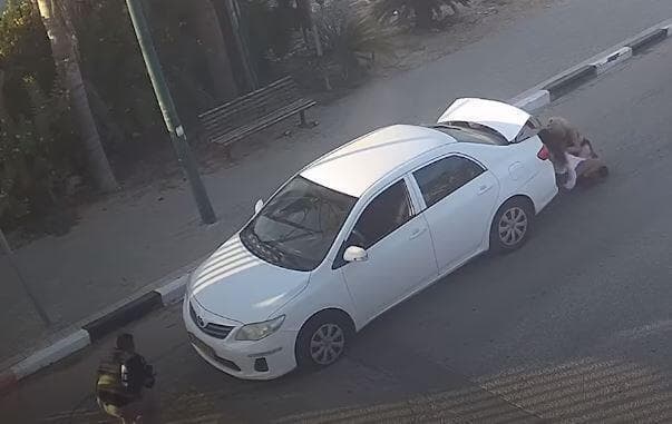 Mujeres israelíes intentan protegerse del ataque de Hamás detrás de un auto. (Captura de video) Mujeres israelíes intentan protegerse del ataque detrás del auto.