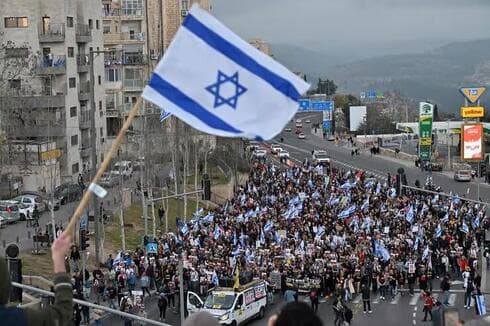 Un asistente ondea una bandera de Israel al paso de los manifestantes. (Alex Kolomoisky) Miles de personas participaron de la marcha.