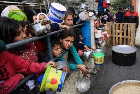 Refugiados palestinos hacen cola para conseguir comida en Rafah. 