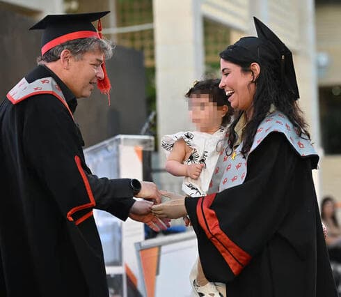 La doctora Eli Hogeg Golan recibe el diploma con su hija en brazos. 