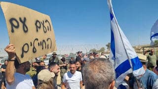 Manifestantes en el centro de detención de Sde Teiman levantan un cartel que dice "Estamos con los soldados". 