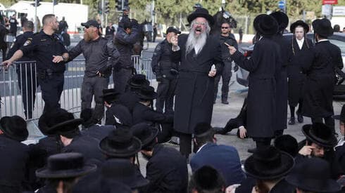 Ultraortodoxos se sientan en el suelo frente a una oficina de reclutamiento. (Reuters) Ultraortodoxos se sientan en el suelo frente la oficina de reclutamiento.