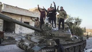 Opositores a Assad celebran arriba de un tanque abandonado por el ejército sirio en la ciudad de Maarat al-Nu'man. 