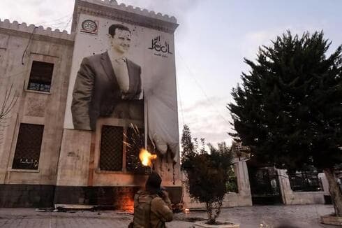 Un jihadista sirio dispara contra la imagen del presidente sirio, Bashar Assad. 