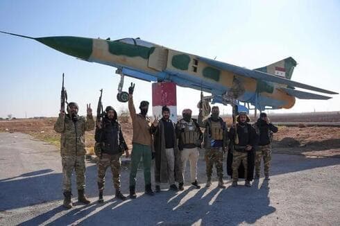 Rebeldes sirios se fotografiaron al lado de un avión de combate, en una base militar cerca de Alepo. 