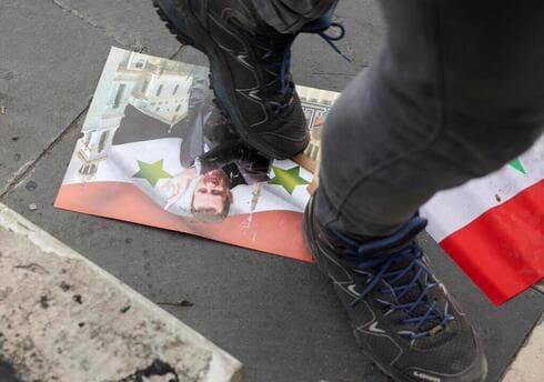 Un soldado camina sobre la foto del ex dictador de Siria. 