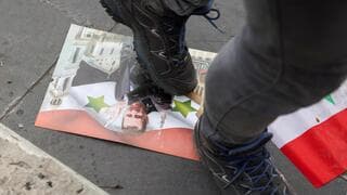 Un soldado camina sobre la foto del ex dictador de Siria. 