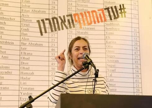 Ayelet Goldin, hermana de Hadar Goldin. "Estamos en una encrucijada histórica". (Dana Koppel) Ayelet Goldin. Detrás, la lista de los 100 secuestrados en poder de Hamás.