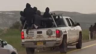 Colonos encapuchados se dirigen a la aldea de Duma. 