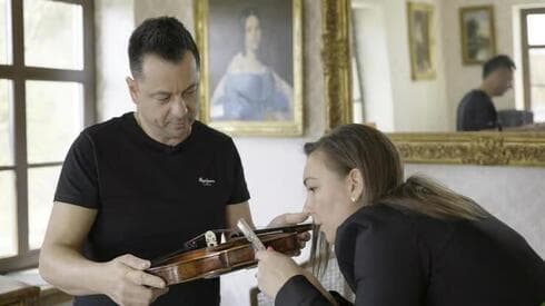 Los coleccionistas de arte Szándra Katona y Thomas Talosi examinan el violín de Dachau. (AP) Violín de Dachau