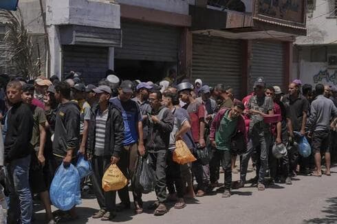 Palestinos hacen cola para acceder a la ayuda humanitaria. 