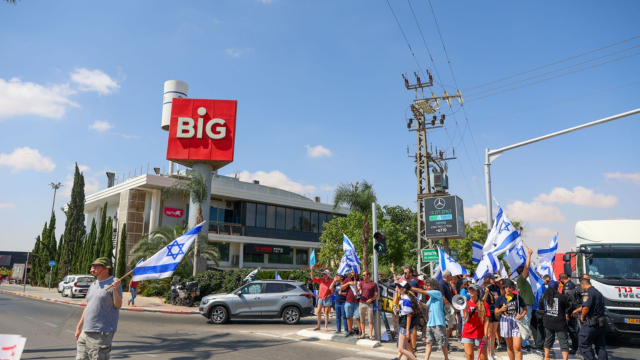 מפגינים על רקע מרכז ביג. המרכז עמד בעין הסערה אך כל העסקים פתחו כרגיל הבוקר