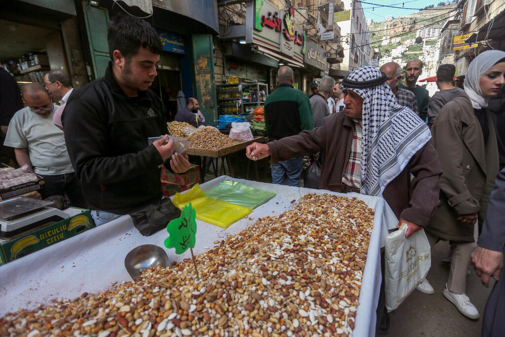فلسطينيون يتسوقون استعدادًا لعيد الفطر في السوق بمدينة نابلس 